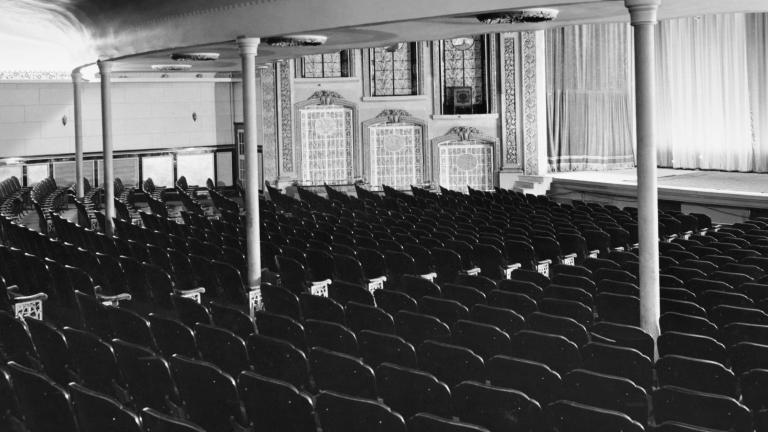 Une photo en noir et blanc de l’intérieur d’une salle de théâtre de style ancien, vide.