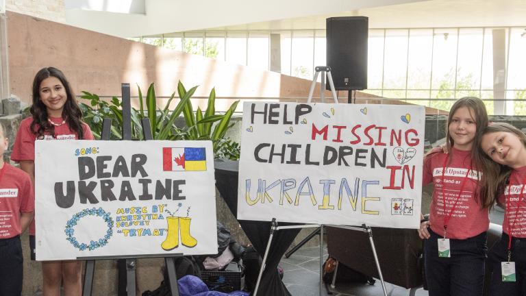 Deux affiches exposées sur des chevalets, avec deux groupes d’élèves debout de chaque côté.