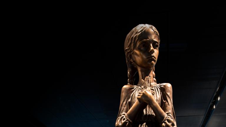 Une statue d’une fillette tenant des épis de blé. Visibilité masquée.