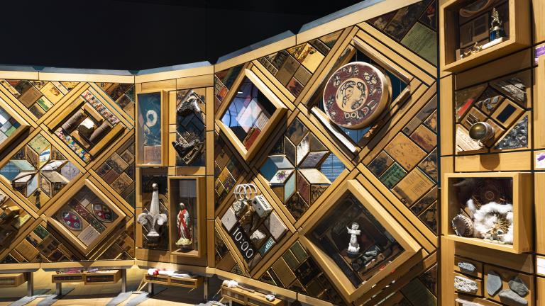 Une grande installation artistique composée de centaine d'objets imbriqués dans un cadre de cèdre rappelant une courte-pointe. Visibilité masquée.