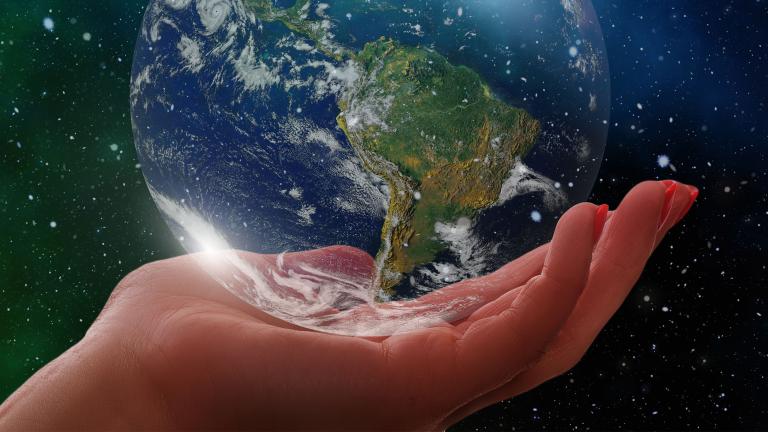Une image stylisée montre une main humaine tenant délicatement un globe terrestre en verre. L’arrière-plan est un ciel nocturne parsemé d’étoiles et d’aurores boréales d’un vert éclatant. Visibilité masquée.