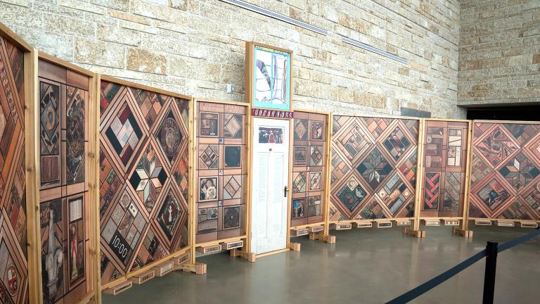 Vue de gauche d’une structure de panneaux de bois verticaux recouverts de motifs d’images, avec une porte blanche au centre.