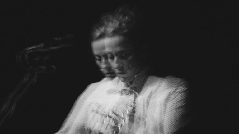 Photo en noir et blanc de Sarah Harmer jouant de la guitare. Deux images floues semblent juxtaposées l’une sur l’autre. Visibilité masquée.