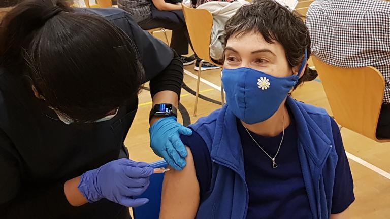 Une travailleuse de la santé se prépare à administrer un vaccin à un patient. Les deux personnes portent des masques médicaux. Visibilité masquée.