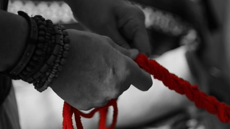 Deux mains en noir et blanc s'accrochent à une corde rouge. Visibilité masquée.