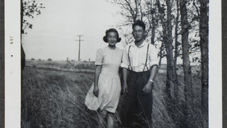 Un jeune couple canadien d’origine japonaise pose dans un champ avec des arbres en arrière-plan. Visibilité masquée.