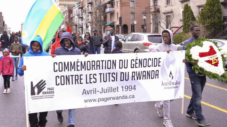 Un groupe de personnes marchant dans la rue avec un bannière sur laquelle on peut lire « Commémoration du génocide contre les Tutsi du Rwanda. Avril-Juillet 1994. www.pagerwanda.ca ». Visibilité masquée.