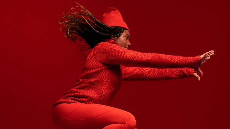 Une femme noire saute dans les airs, vêtue d'un uniforme olympique entièrement rouge. Visibilité masquée.