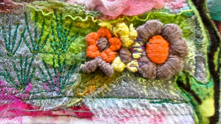 Une œuvre d’art textile colorée qui comprend des fleurs brodées, des branches et de la verdure mélangées à des couches de tissus roses, bleus et blancs. Visibilité masquée.