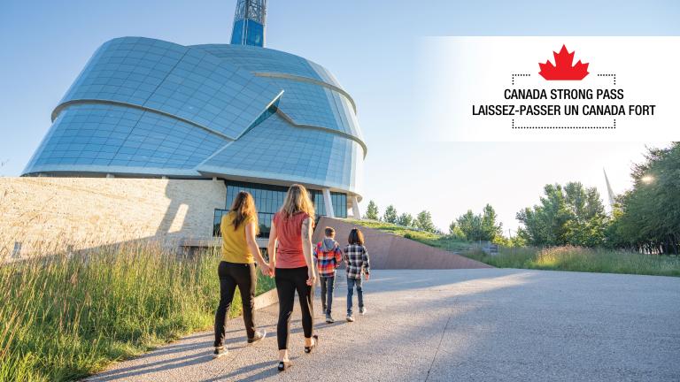 Un groupe de personnes se dirige vers un bâtiment en verre entouré de verdure. En haut de l'image, on peut lire « Laissez-passer un Canada fort » en anglais et en français. Visibilité masquée.