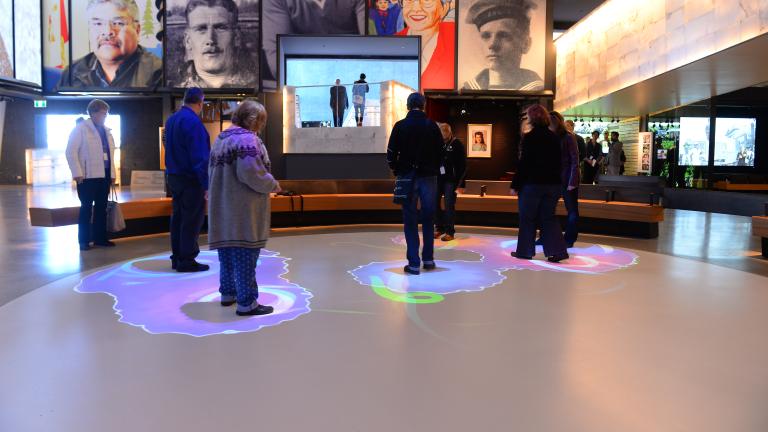 Un groupe de personnes se tient dans une partie d'un cercle blanc. Des lumières bleues et violettes sont projetées sur le sol autour de chaque personne.