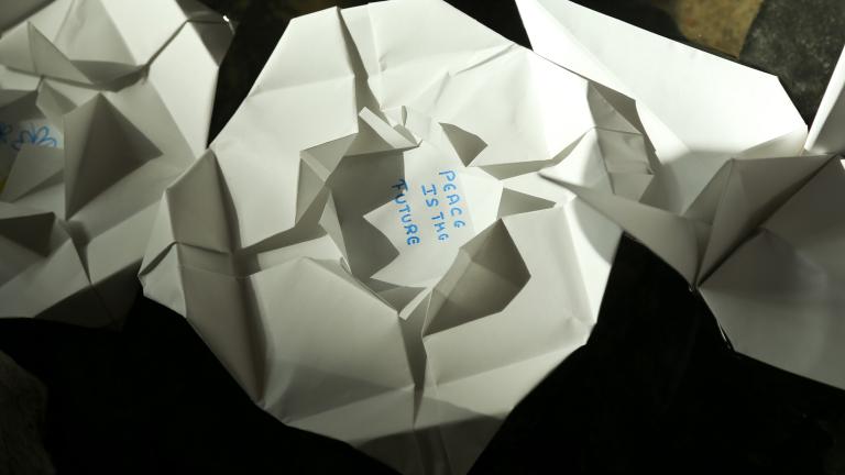  Folded paper lilies floating in water. “Peace is the future” is written in the centre of one lily. Visibilité masquée.