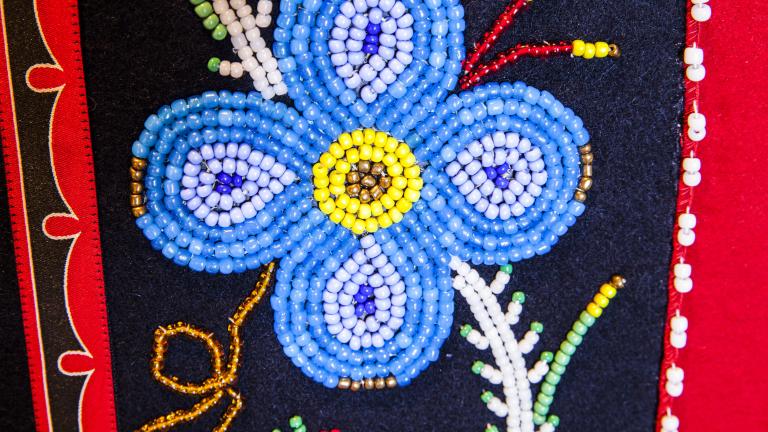 A blue beaded flower on a black and red background. Visibilité masquée.