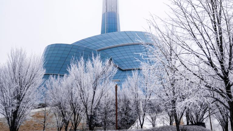 Un édifice de forme inhabituelle enveloppé d'un « nuage » de verre et surmonté d'une tour. Il est entouré de neige et d'arbres nus. Visibilité masquée.