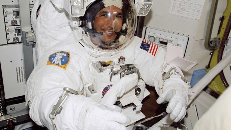 Un homme souriant dans un uniforme d'astronaute. Visibilité masquée.