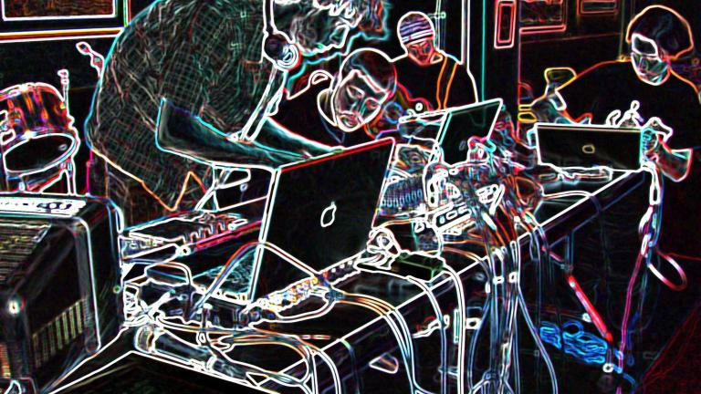 Quatre personnes autour d’une table recouverte d’ordinateurs et d’équipement de musique électronique. La photo a été modifiée de façon à ce que l’arrière-plan soit noir et les éléments de la photo, surlignés en néon multicolore. Visibilité masquée.