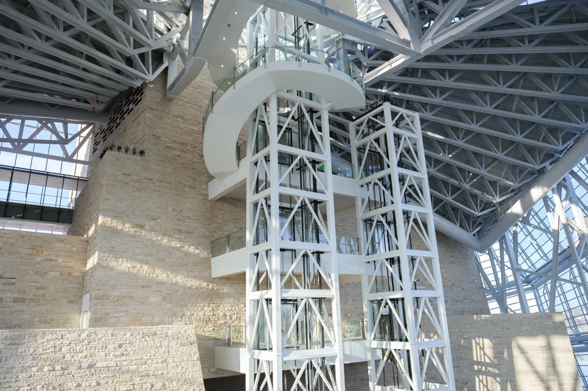 L’intérieur d’un grand espace ouvert du Musée avec deux cages d’ascenseur au centre de l’image, ainsi qu’un mur de calcaire.