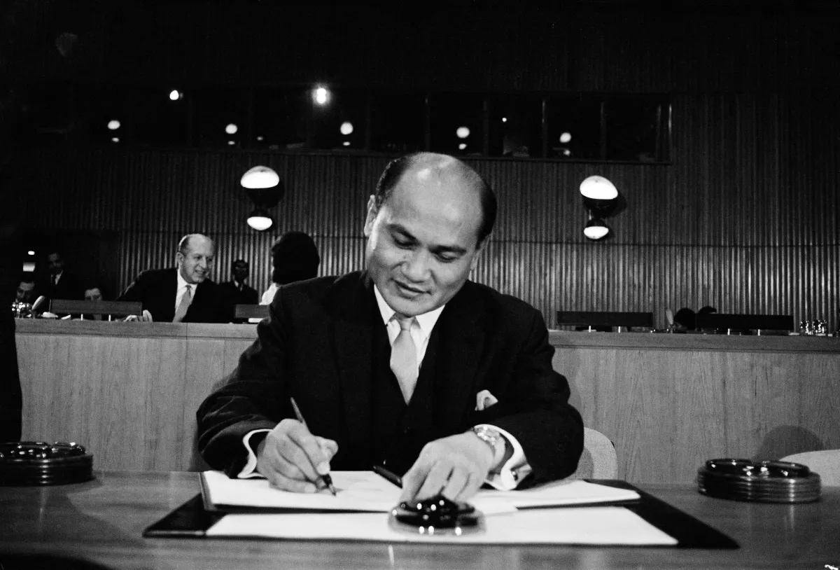 Un homme en complet signe un document.