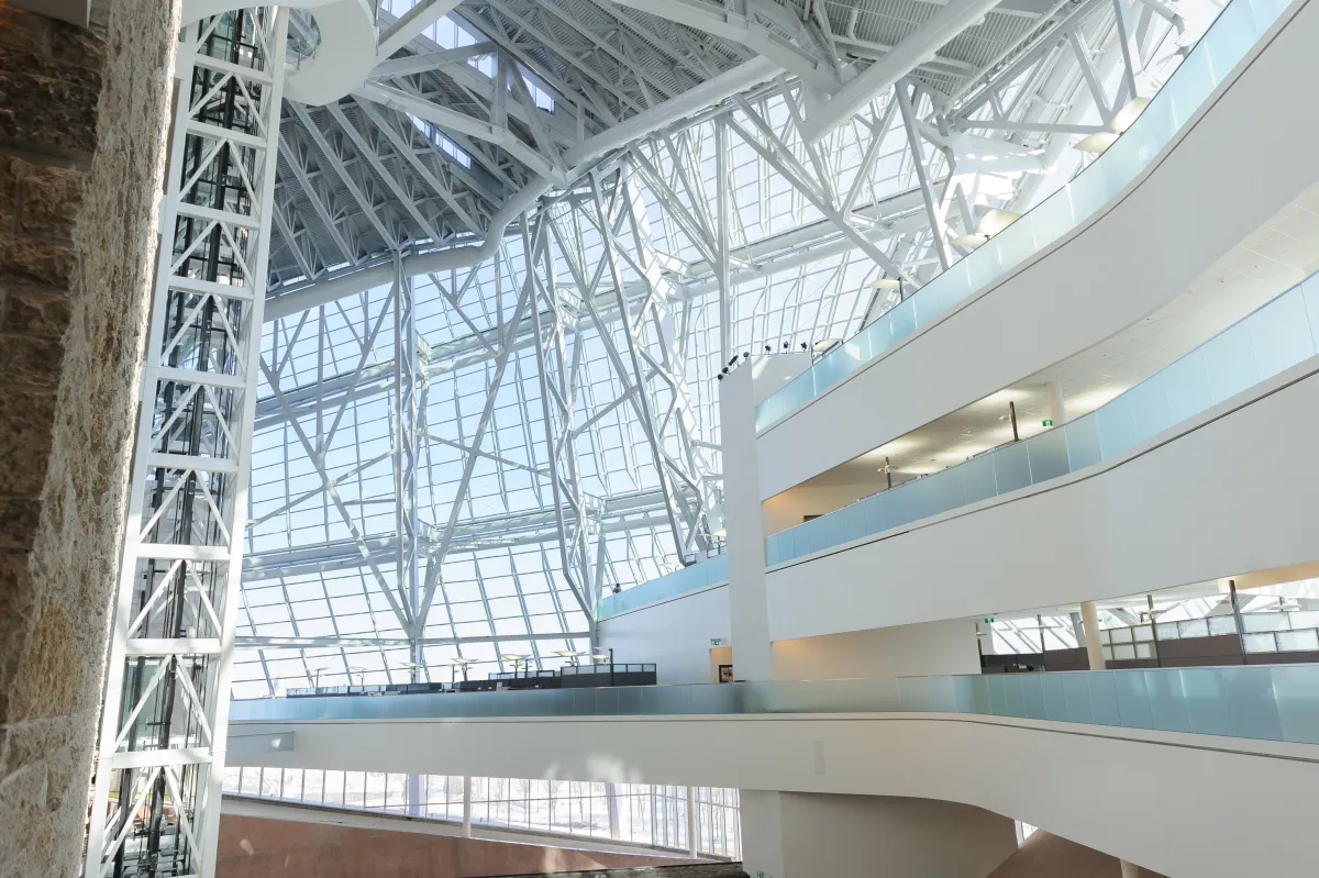 L’intérieur d’un grand espace ouvert du Musée. On voit des panneaux de verre et une terrasse blanche à trois niveaux.