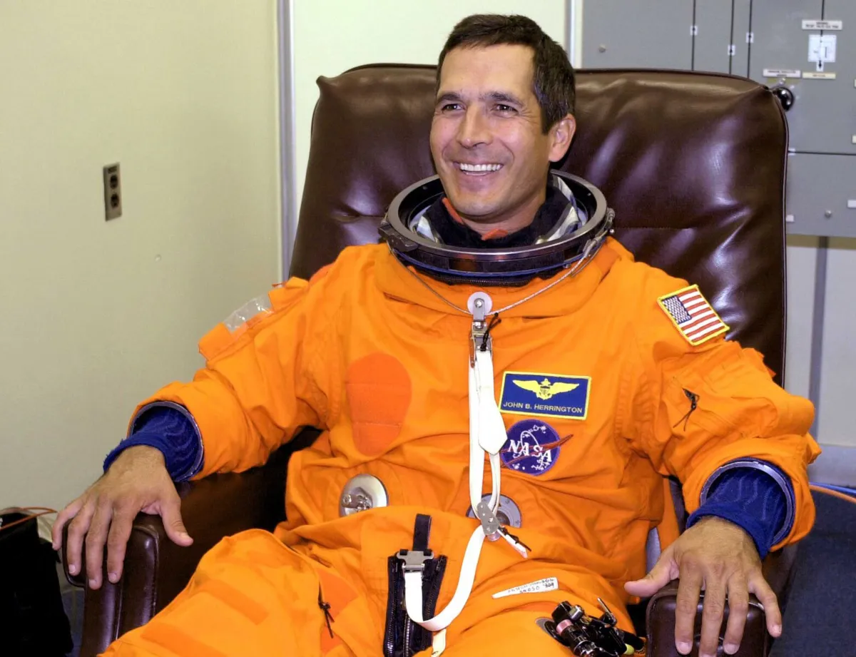 Un homme souriant dans un uniforme d'astronaute orange.
