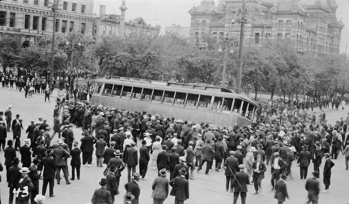 Une grande foule de gens essayant de renverser un tramway.