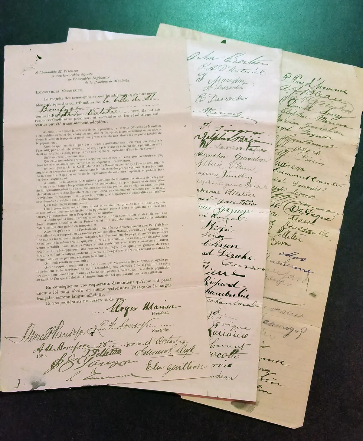 Gros plan d’une pétition originale de langue française avec deux pages de signatures placées en éventail en dessous.