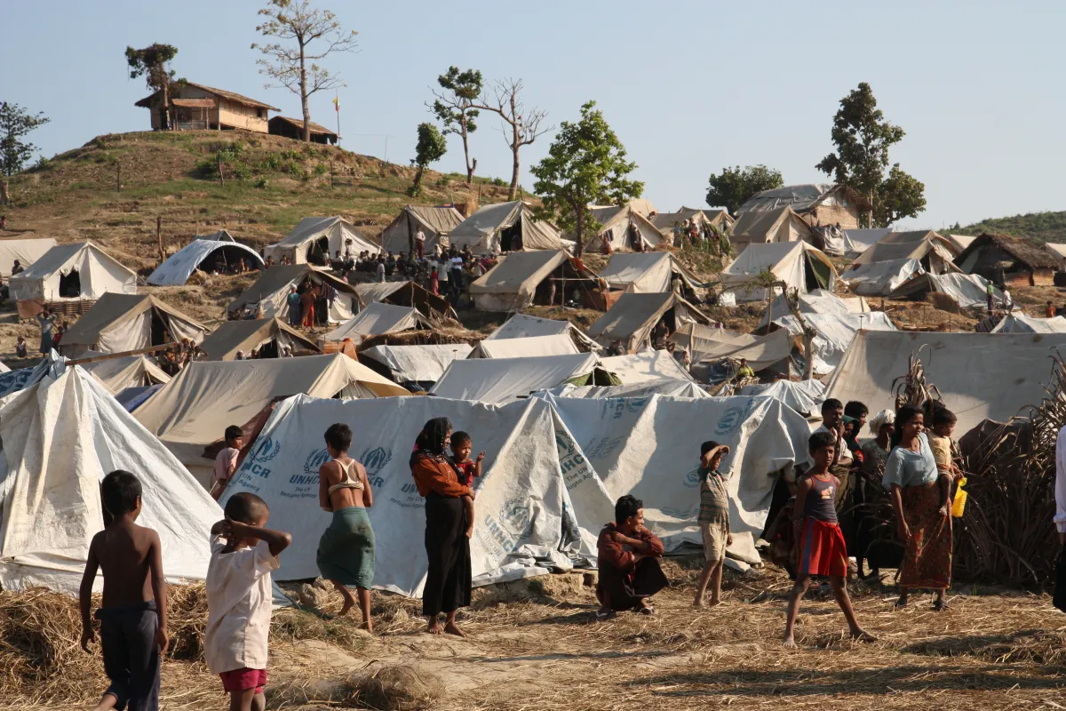 Camp densément recouvert de tentes de toile, à flanc de colline. On y voit de nombreux réfugiés tant à l’intérieur qu’à l’extérieur des tentes.