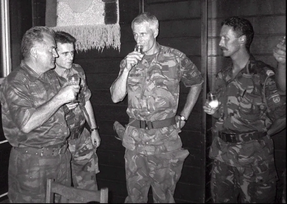 Quatre hommes portant des uniformes militaires de camouflage debout ensemble, tenant des boissons.