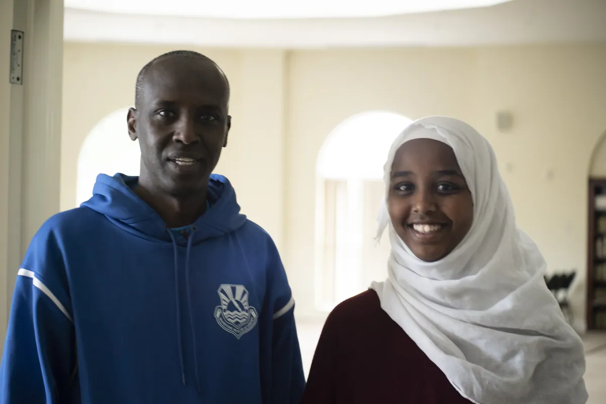 Un homme se tient à côté d’une jeune femme portant un hidjab.