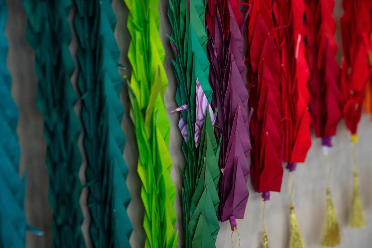 Un gros plan de quelques-unes des grues en papier plié coloré qui font partie d'une installation regroupant mille grues.
