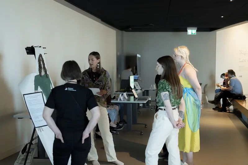 Dans une galerie de musée, une élève parle à trois autres personnes. Elle est debout près d’un dessin grandeur nature d’elle-même.