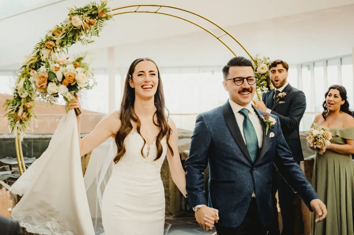 Un homme en costume et une femme en robe de mariée se tiennent par la main.