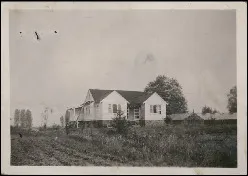 Image en noir et blanc d’une maison de ferme dans un champ.