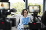 Femme assise sur un canapé devant deux caméras vidéo.