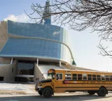 Un autobus scolaire jaune est stationné devant le Musée. 