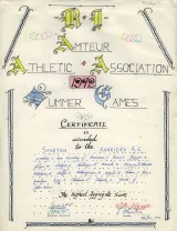 Certificat rédigé à la main en caractères stylisés. Il est écrit surtout à l’encre noire et quelques lettres sont colorées en bleu ou en jaune. Dans le haut du certificat, on peut lire « R.I. Amateur Athletic Association 1972 Summer Games. »