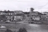 Une image en noir et blanc d’une douzaine de maisons sur une colline. Au milieu de l’image, on voit un chemin de terre qui monte la colline entre les maisons.