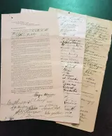 Gros plan d’une pétition originale de langue française avec deux pages de signatures placées en éventail en dessous.