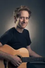 Un homme joue une guitare acoustique.