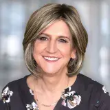 Une femme portant une chemise fleurie, regarde vers l'objectif.