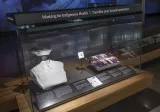 Une vitrine du Musée intitulée « Travailler pour la santé autochtone » et contenant l’uniforme et l’épinglette de diplômée d’une infirmière et une photo de groupe. 