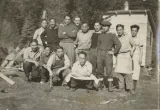 Un groupe d’hommes pose pour une photo avec des arbres en arrière-plan.