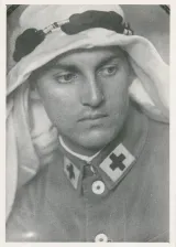 Un homme blanc en uniforme militaire avec une croix noire au bord du col porte un keffieh, une pièce en coton blanc portée au Moyen-Orient.