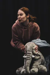 Une femme est penchée sur un grand toutou éléphant qu'elle serre entre ses mains.