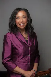 Une femme noire sourit vers l’objectif.