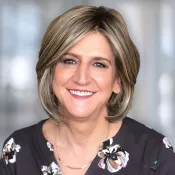 Une femme portant une chemise fleurie, regarde vers l'objectif.