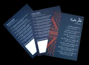 Trois cartes sont posées à plat sur une table noire. Chaque carte porte le poème « Pense aux autres » de Mahmoud Darwich. La carte de gauche présente la traduction du poème en français. Celle du centre présente la traduction en anglais. La carte de droite, visible dans son intégralité, présente le poème original en arabe.