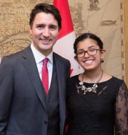 Le premier ministre Justin Trudeau, à gauche, et Nimrat Randhawa, à droite, p posent pour une photo devant le drapeau canadien. Ils sourient tous deux au photographe.