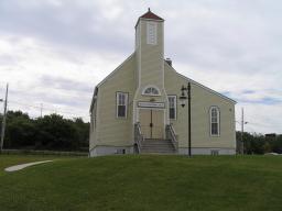  Image d’une église en bois à un seul clocher. Un panneau placé au-dessus des portes principales et à la base du clocher porte l’inscription « Seaview United Baptist Church ».
