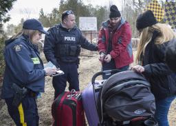 Des policiers arrêtant des demandeurs d’asile parce qu’ils traversent la frontière canado-américaine.